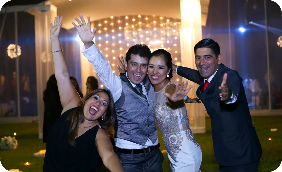 Magaly Ponce in black posing with the bride and groom, along with two friends, at a joyful wedding reception.